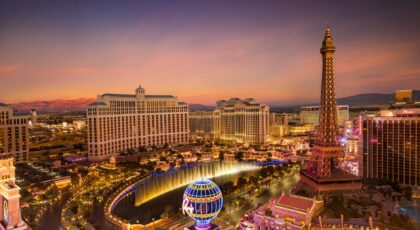 Stunning aerial view of Las Vegas skyline at sunset, featuring the Eiffel Tower and Bellagio fountains.