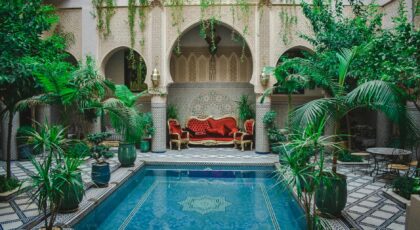 Elegant Moroccan courtyard featuring lush greenery and a decorative pool, perfect for a serene escape.