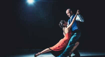 Elegant couple performing tango under a dramatic spotlight, showcasing passion and grace.