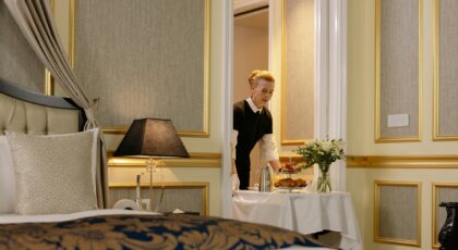 A hotel employee delivers elegant room service with a tray of breakfast in a luxurious hotel setting.