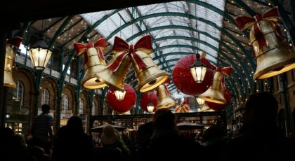 A vibrant scene of Christmas decorations in Covent Garden Market, London, with festive bells and ribbons.