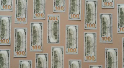 Flatlay of hundred dollar bills arranged on a surface representing wealth and finance.