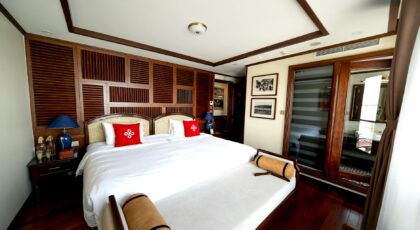 A luxurious hotel room featuring elegant wooden decor and a comfortable double bed with red accents.
