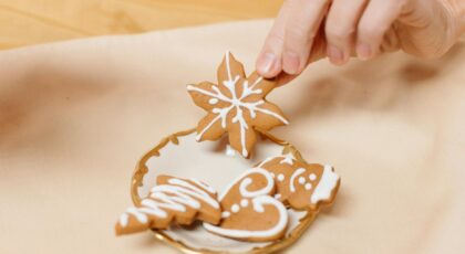 A hand picking beautifully decorated gingerbread cookies from a golden plate, perfect for holiday celebrations.