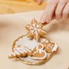 A hand picking beautifully decorated gingerbread cookies from a golden plate, perfect for holiday celebrations.
