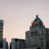 Iconic Fairmont Royal York hotel among modern skyscrapers at dusk in Toronto.