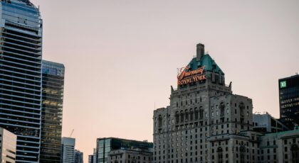 Iconic Fairmont Royal York hotel among modern skyscrapers at dusk in Toronto.