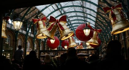 A vibrant scene of Christmas decorations in Covent Garden Market, London, with festive bells and ribbons.