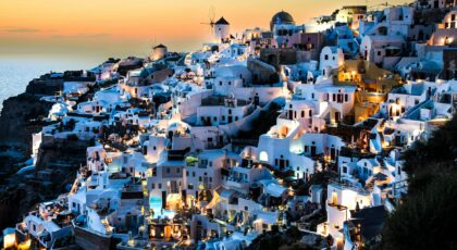 Explore the stunning view of Oia, Santorini, with illuminated white buildings at twilight.