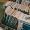 A collection of books neatly arranged in a suitcase next to a potted plant on a wooden table, creating a cozy indoor setting.