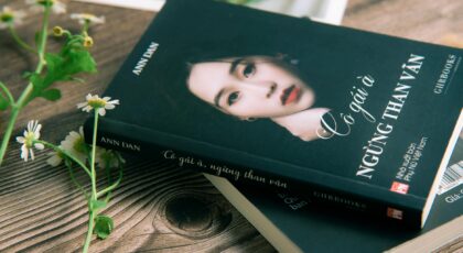 Close-up of a Vietnamese book cover with a portrait of a woman alongside daisies on a wooden table.