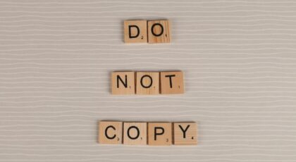 Close-up of wooden tiles spelling 'Do Not Copy' on a textured surface.
