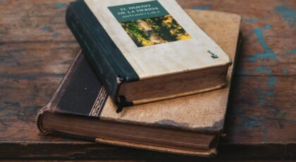 Two vintage books with worn covers on a rustic wooden table, exuding timeless charm.