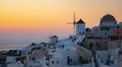 Experience the stunning sunset in Santorini, Greece, showcasing iconic white architecture and windmills.