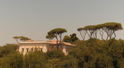 Charming villa surrounded by pine trees in a Mediterranean environment, evoking classic Italian architecture.